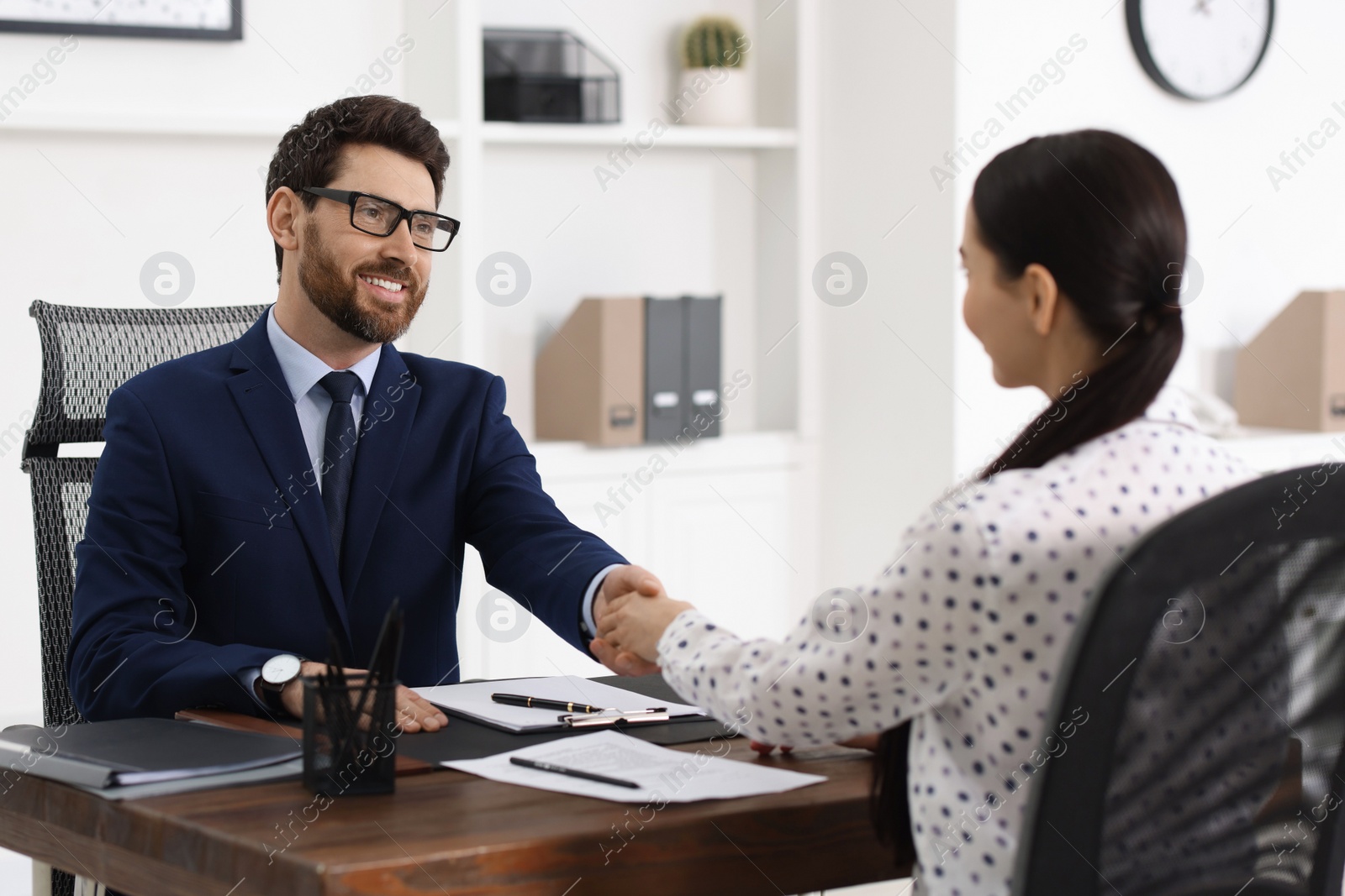 Photo of Lawyer shaking hands with client in office, selective focus