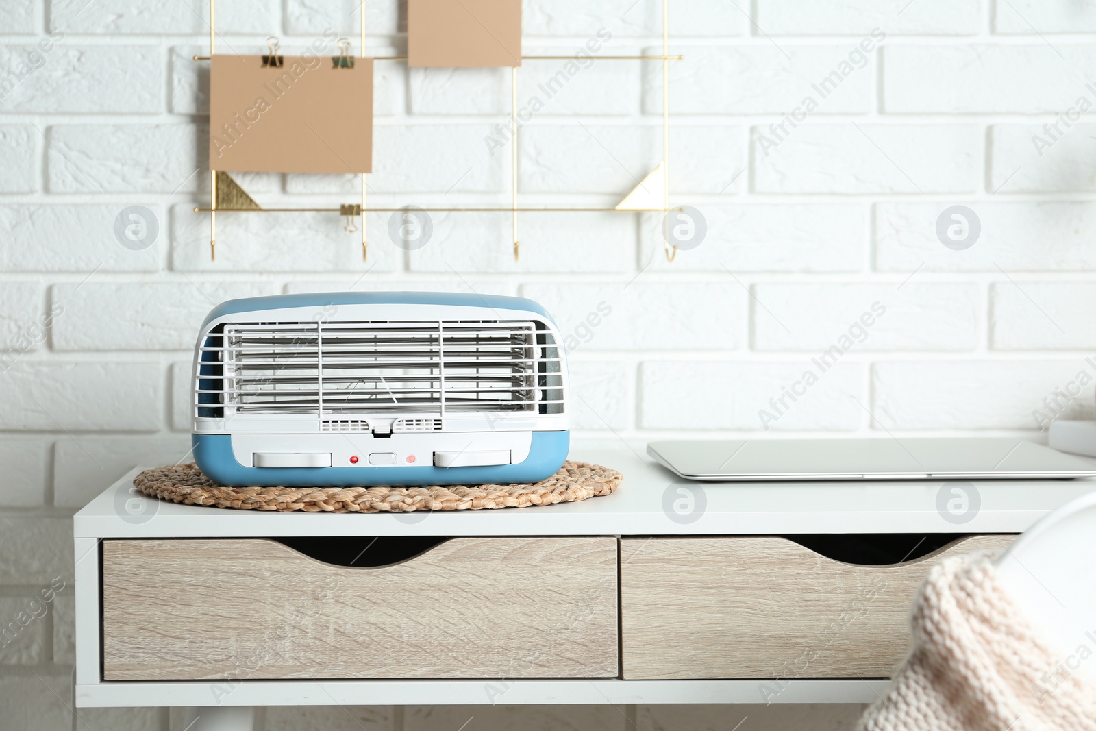 Photo of Modern air purifier near laptop on white wooden table in room