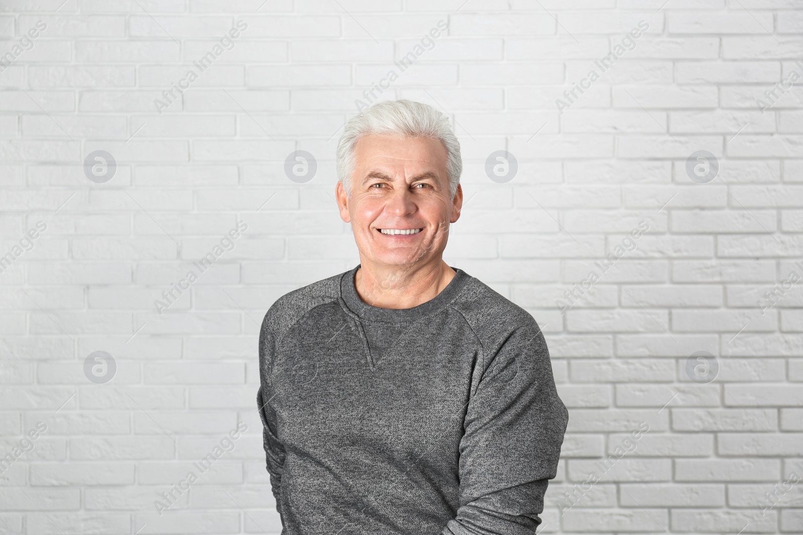 Photo of Portrait of handsome mature man near brick wall