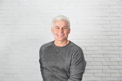 Portrait of handsome mature man near brick wall