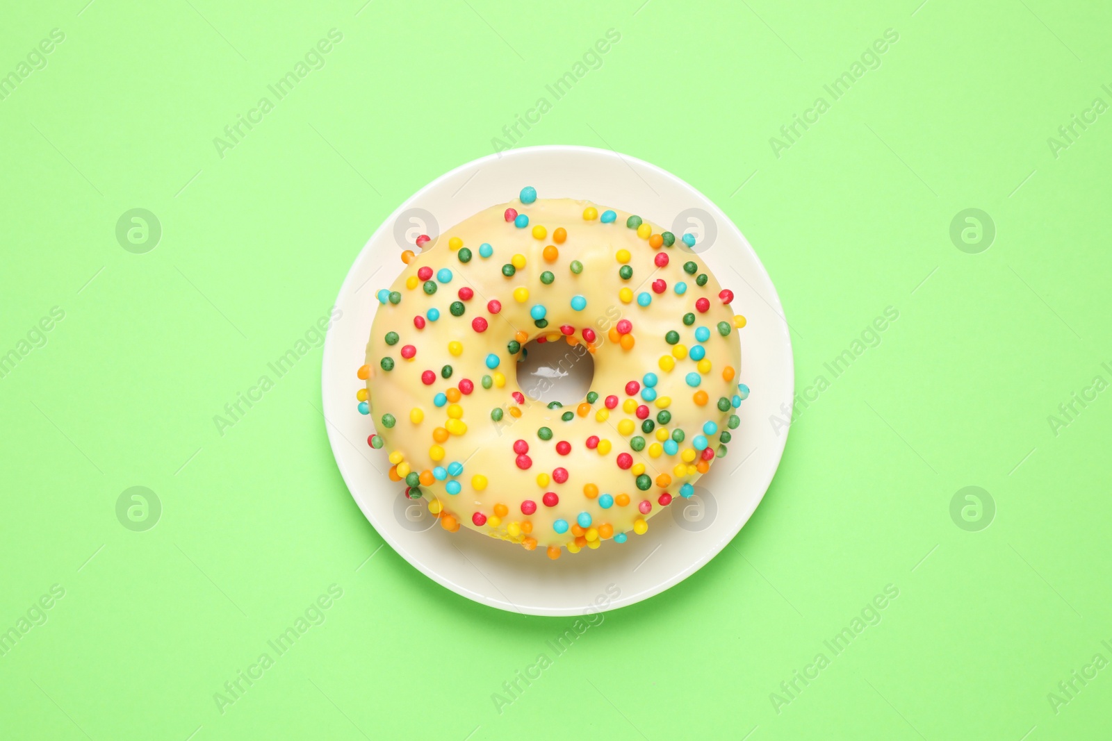 Photo of Delicious glazed donut on green background, top view