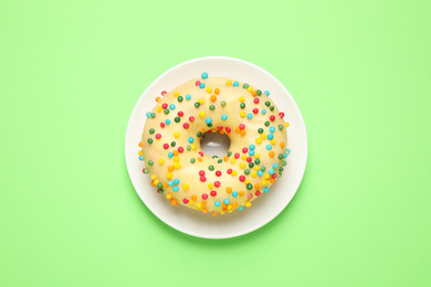 Photo of Delicious glazed donut on green background, top view