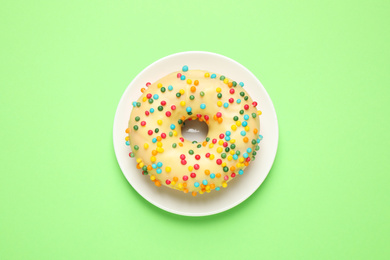 Delicious glazed donut on green background, top view