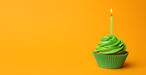 Photo of Delicious birthday cupcake with green cream and burning candle on yellow background. Space for text
