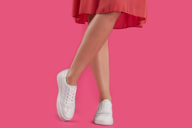 Photo of Woman wearing shoes on pink background, closeup