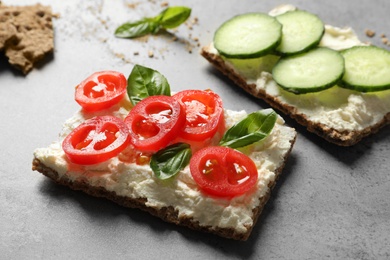 Photo of Tasty snacks with cream cheese and vegetables on gray table