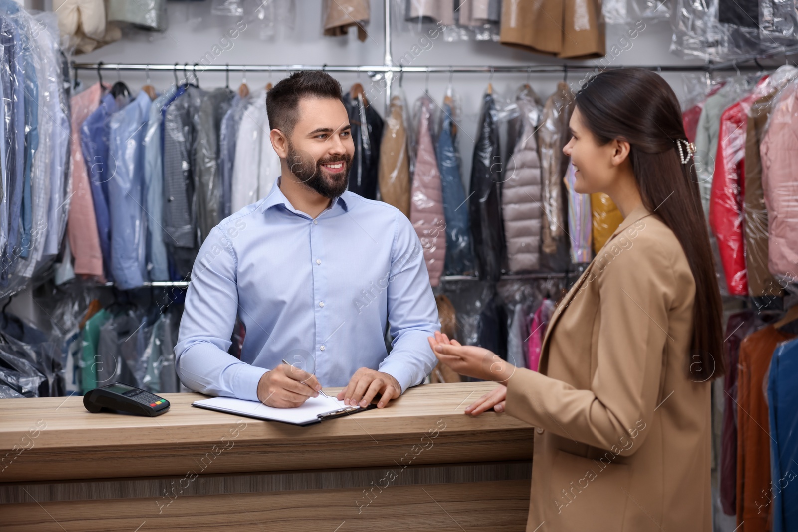 Photo of Dry-cleaning service. Happy man working with client indoors