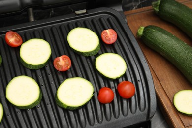 Photo of Electric grill with vegetables on black table, closeup