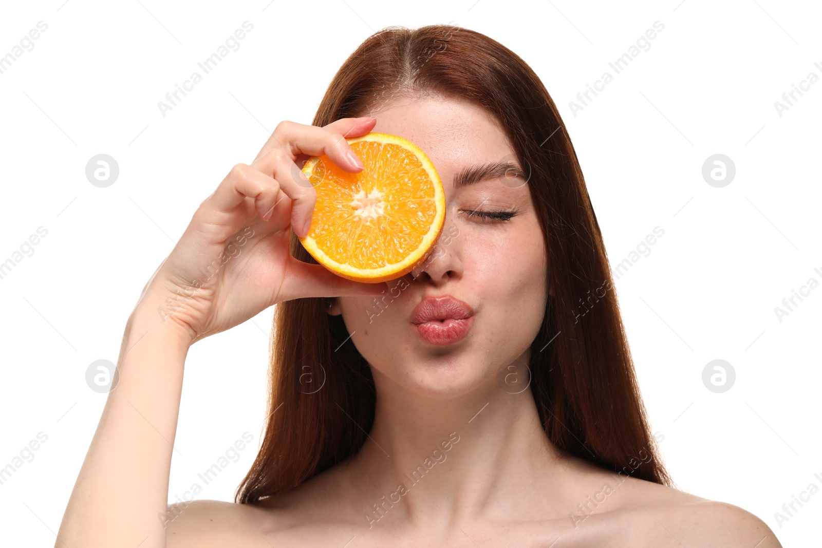Photo of Beautiful woman covering eye with half of orange and sending air kiss on white background