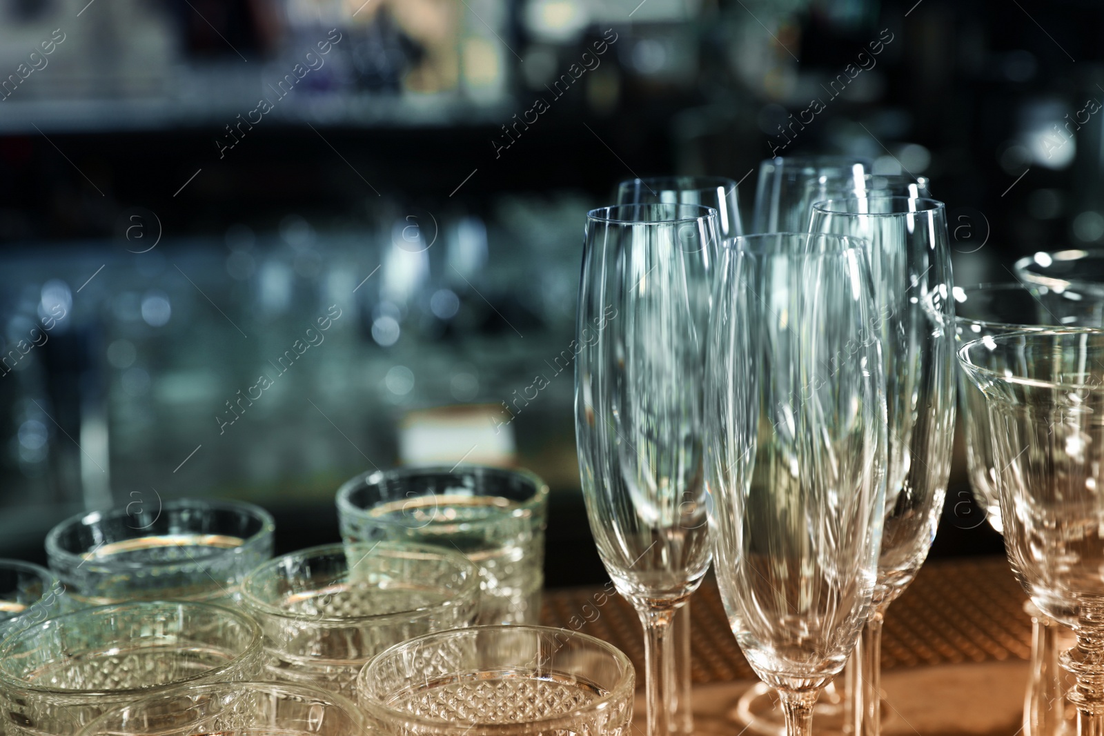 Photo of Different empty clean glasses on counter in bar, closeup