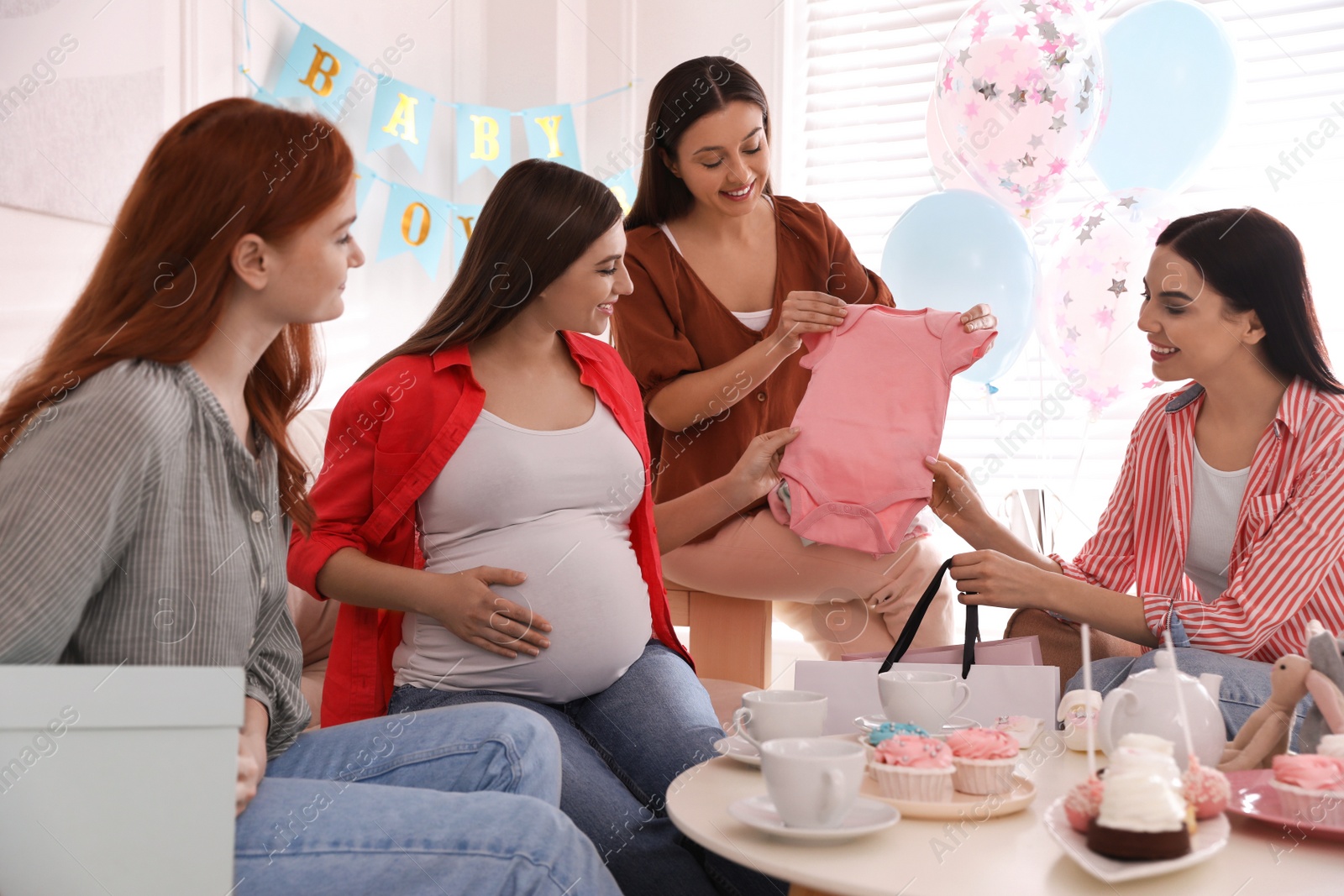 Photo of Happy pregnant woman spending time with friends at baby shower party