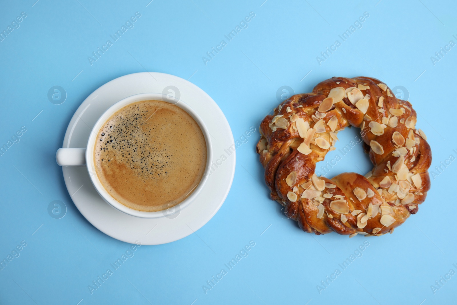 Photo of Delicious coffee and pastry on light blue background, flat lay