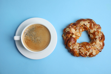 Delicious coffee and pastry on light blue background, flat lay