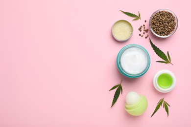 Different hemp cosmetics, green leaves and seeds on pink background, flat lay. Space for text