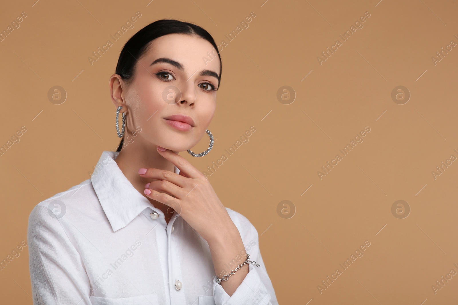 Photo of Beautiful young woman with elegant jewelry on beige background. Space for text