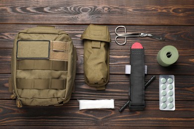 Photo of Military first aid kit on wooden table, flat lay