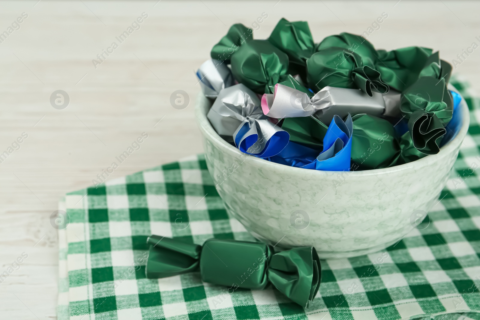 Photo of Candies in colorful wrappers on white wooden table