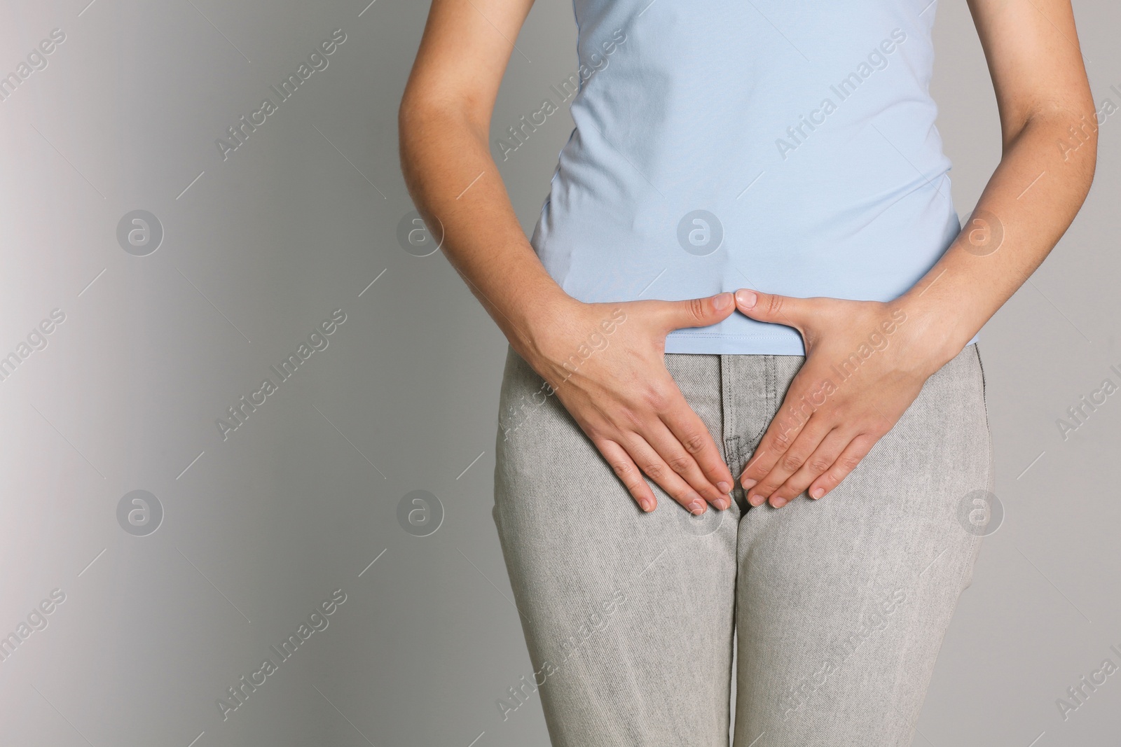 Photo of Woman suffering from genital herpes on light grey background, closeup. Space for text