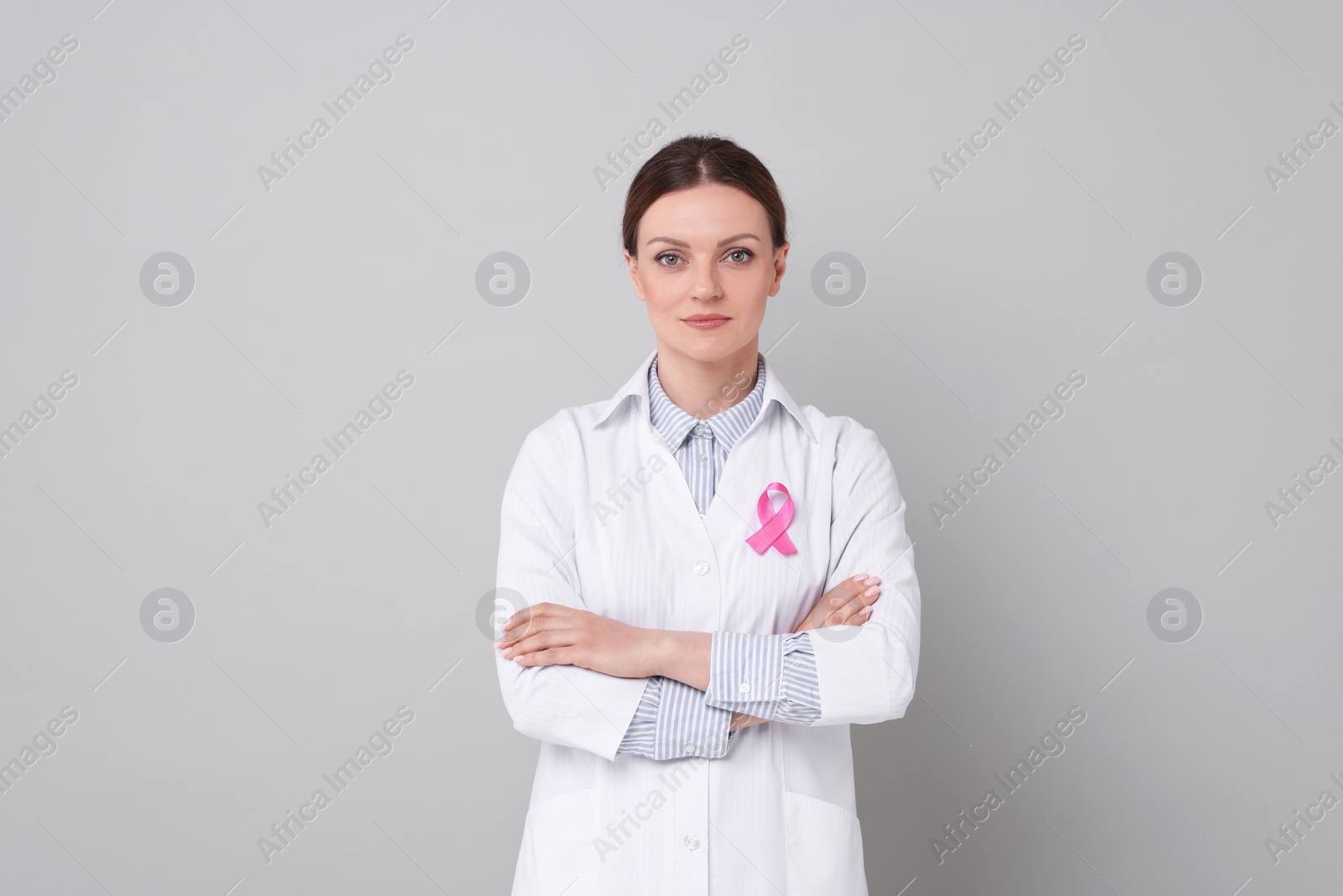 Photo of Mammologist with pink ribbon on grey background. Breast cancer awareness