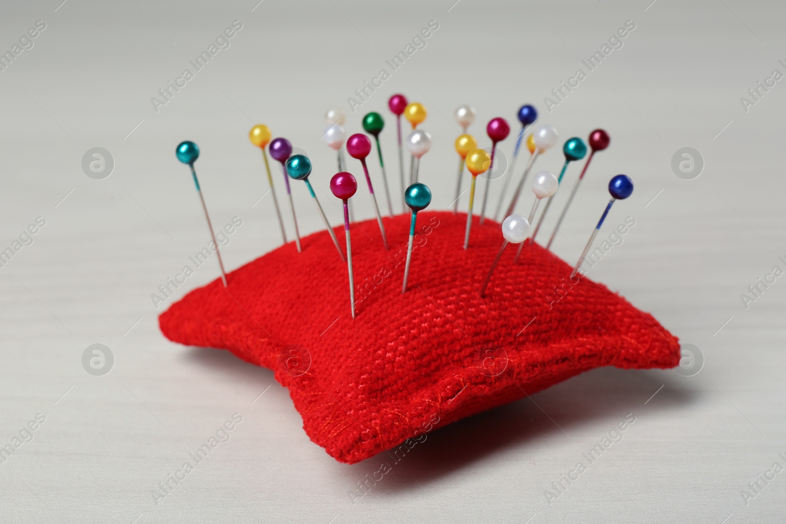 Photo of Red cushion with pins on white table