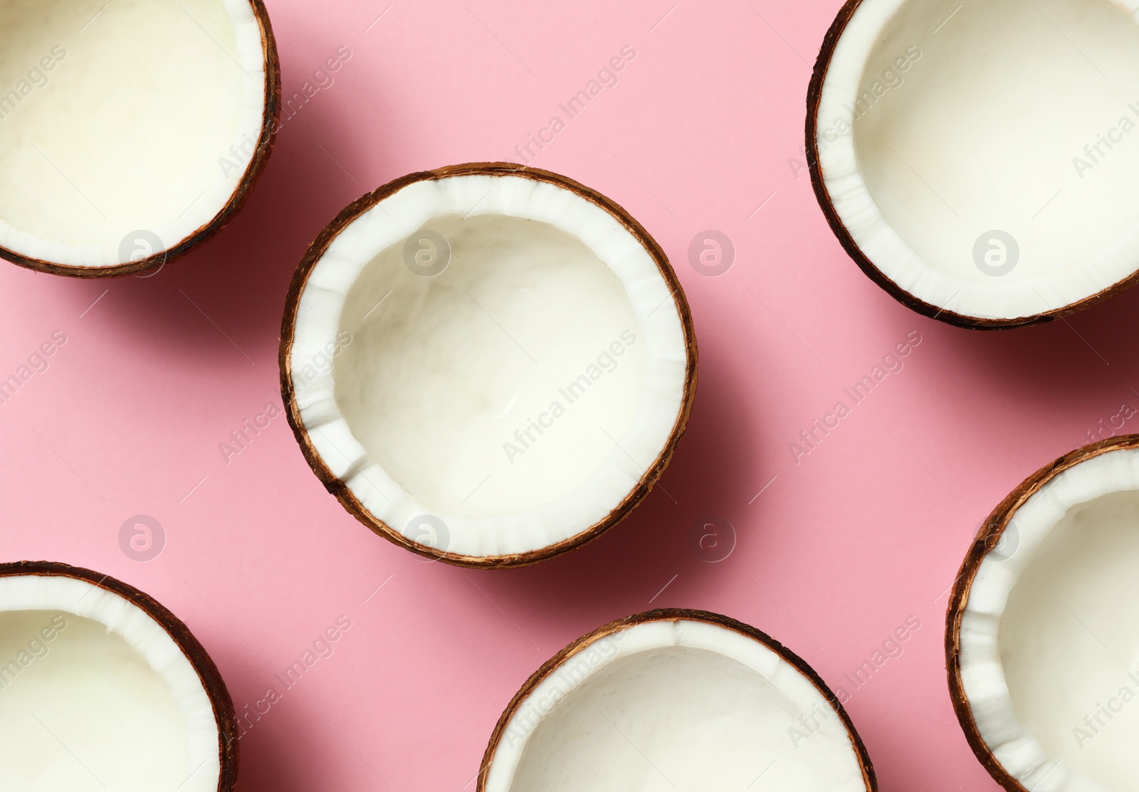 Photo of Fresh coconut halves on pink background, flat lay