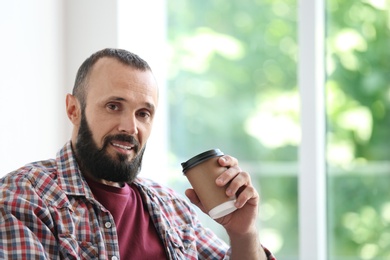Photo of Portrait of handsome mature man with coffee near window