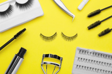 Flat lay composition with fake eyelashes, brushes and tools on yellow background