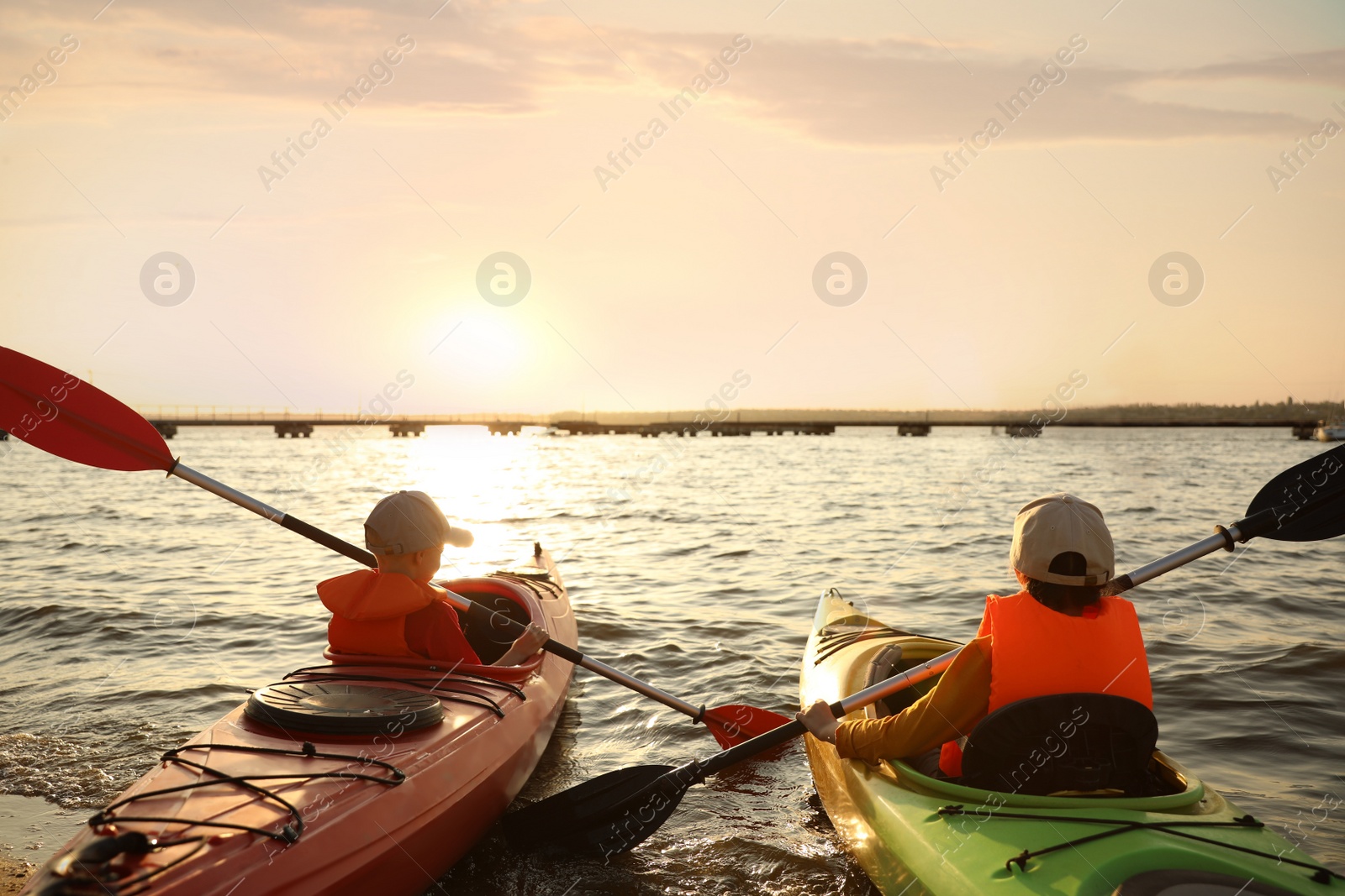 Photo of Little children kayaking on river, back view. Summer camp activity