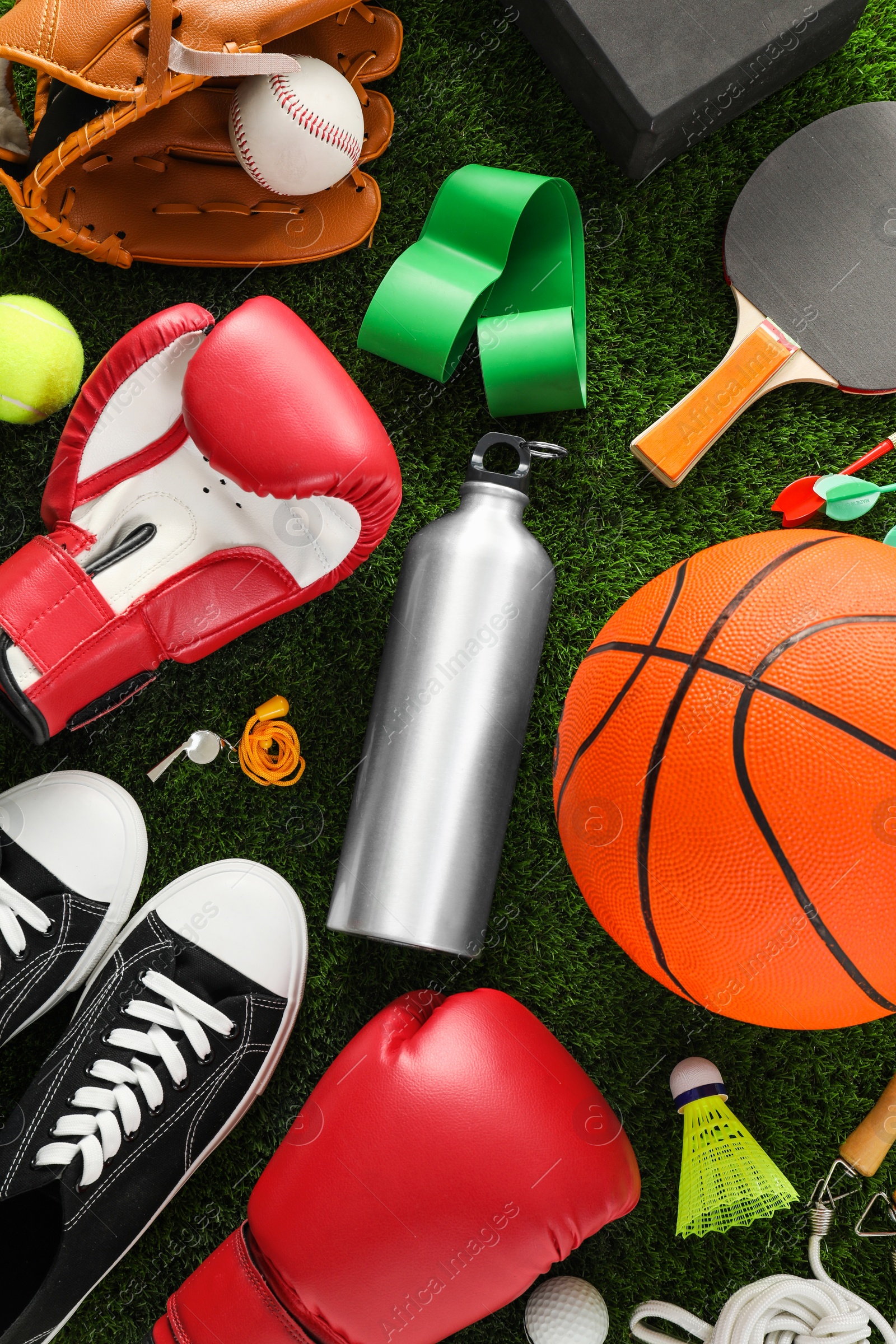 Photo of Different sport equipment and sneakers on green grass, flat lay