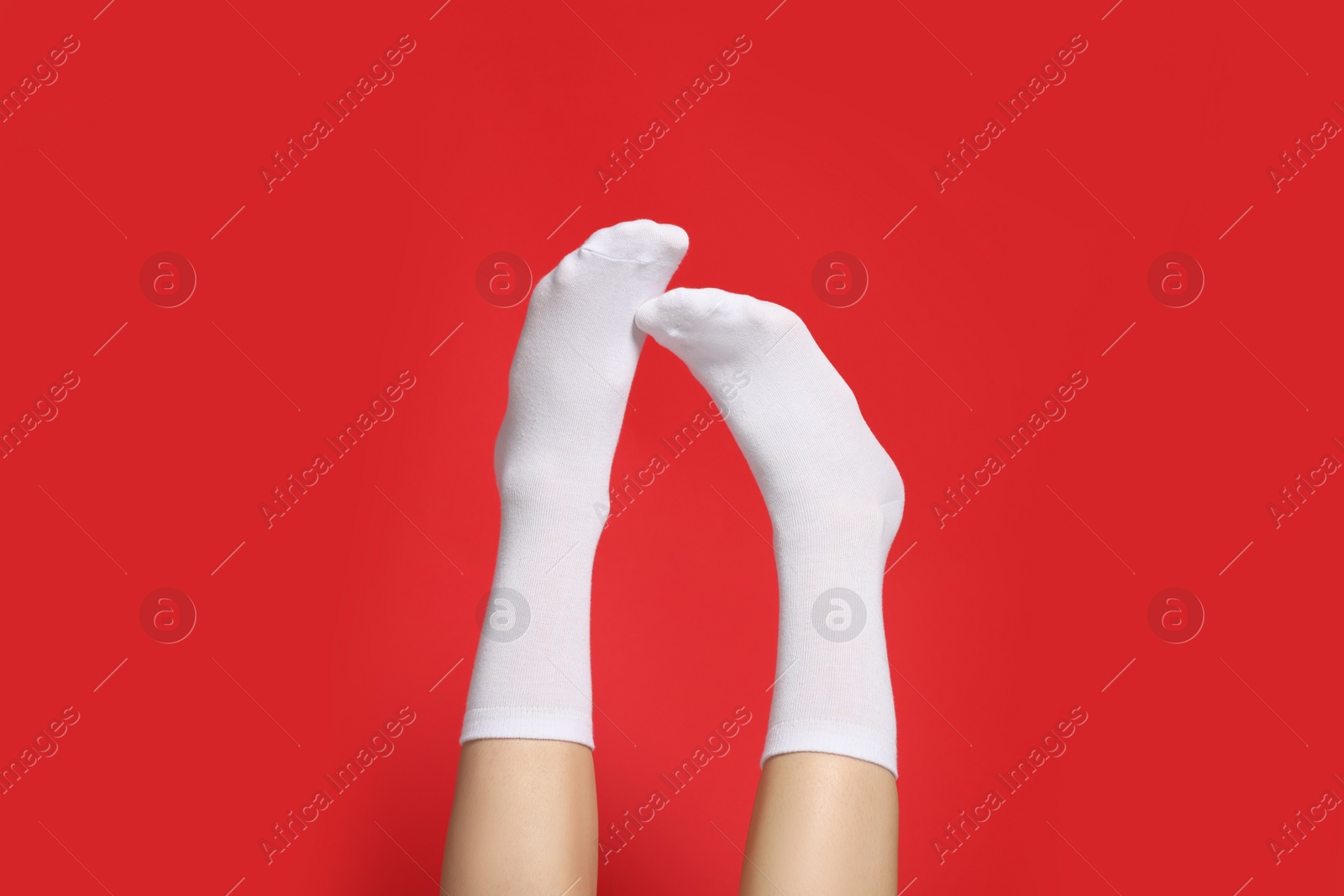 Photo of Woman in stylish white socks on red background, closeup