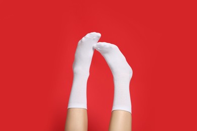 Photo of Woman in stylish white socks on red background, closeup