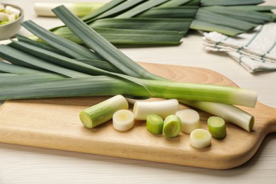Whole and cut fresh leeks on white wooden table, closeup