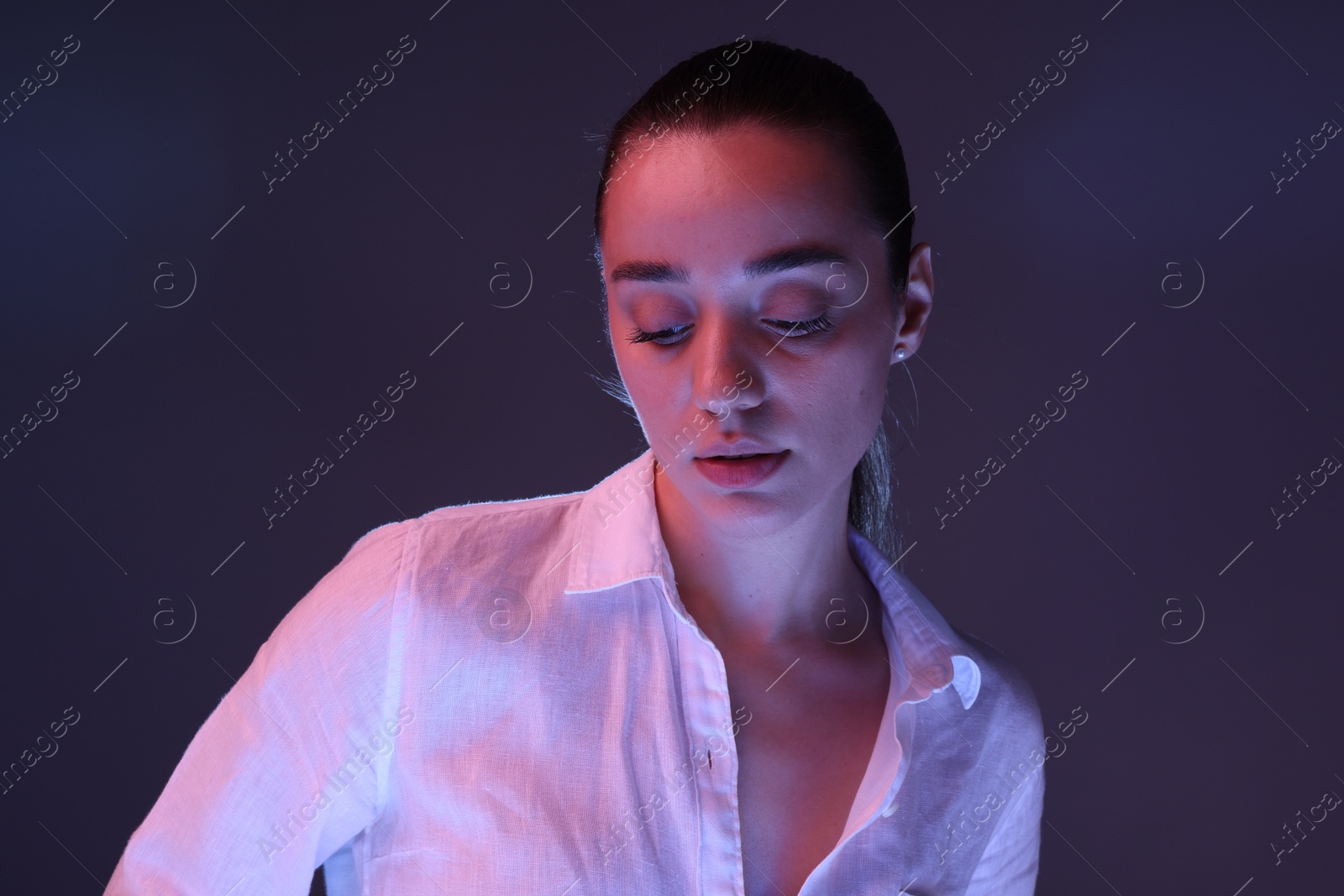 Photo of Portrait of beautiful young woman on dark purple background with neon lights