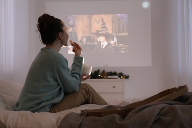 Photo of Lviv, Ukraine – January 24, 2023: Woman with marshmallows watching Harry Potter And The Philosopher’s Stone movie via video projector at home