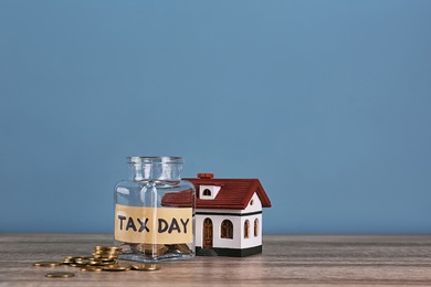 House model, glass jar with label "TAX DAY" and coins on table