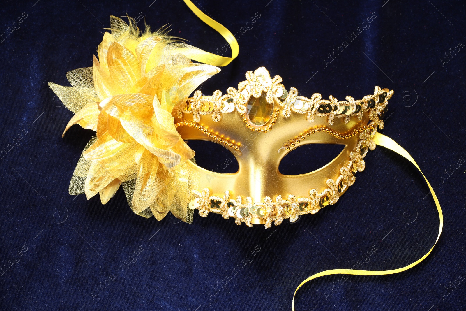 Photo of Theater arts. Golden venetian carnival mask on blue fabric, top view