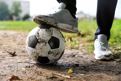 Photo of Man with dirty soccer ball outdoors, closeup