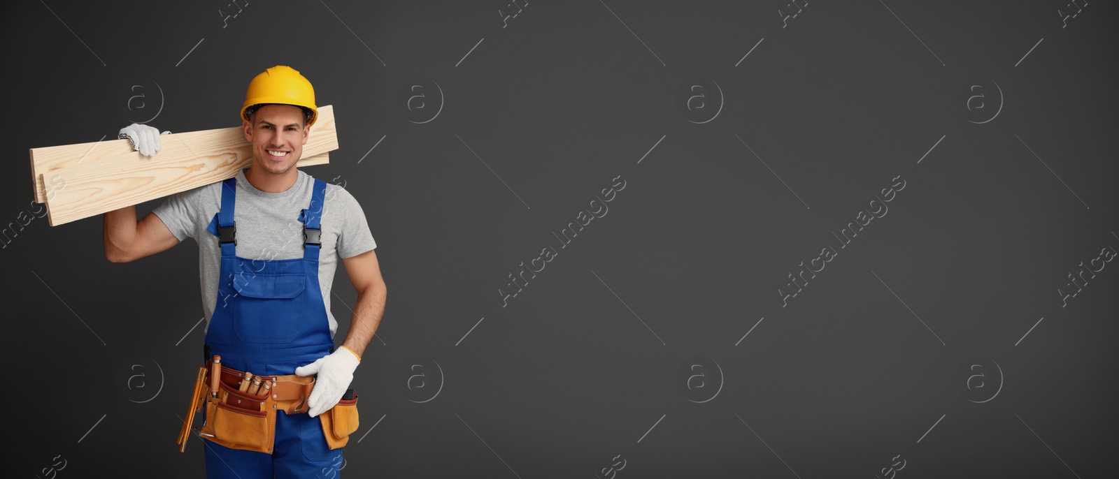 Image of Handsome carpenter with wooden planks on dark background, space for text. Banner design