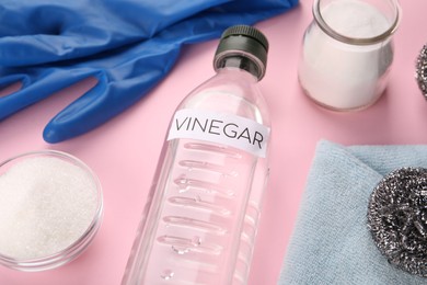 Photo of Eco friendly natural cleaners. Vinegar in bottle, soda and gloves on pink background