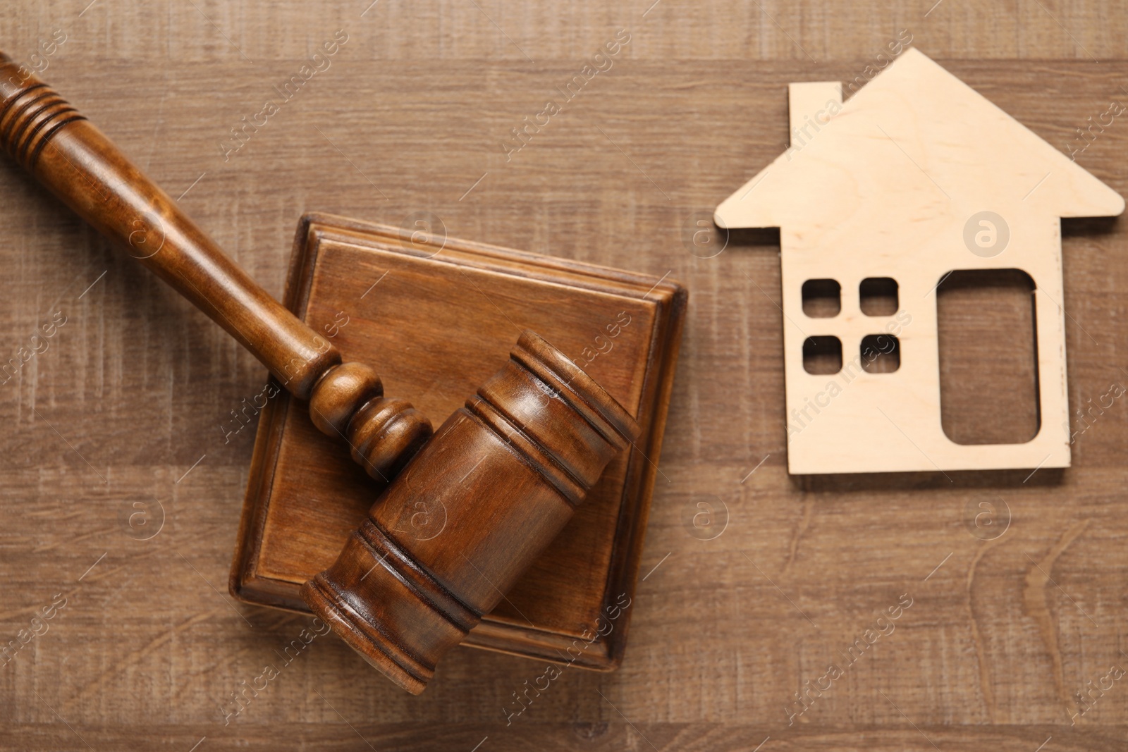 Photo of Law concept. Gavel and figure of house on wooden table, top view