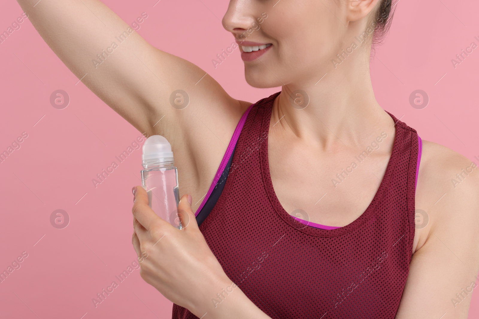 Photo of Beautiful woman applying deodorant on pink background