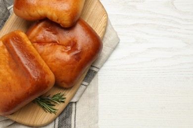 Photo of Delicious baked patties with rosemary branches on white wooden table, top view. Space for text