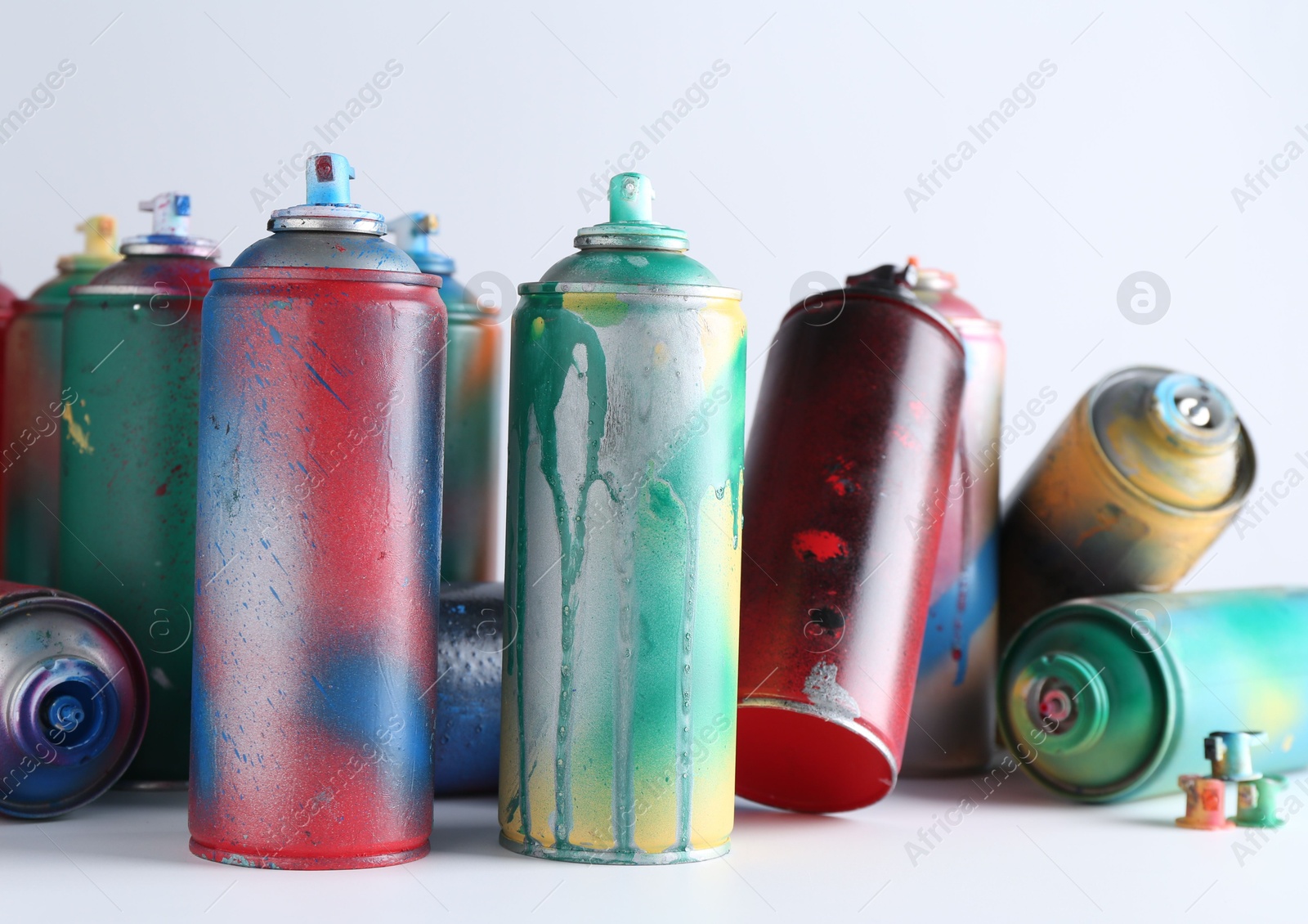 Photo of Many spray paint cans on white background, closeup