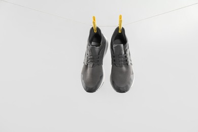 Photo of Stylish sneakers drying on washing line against light grey background