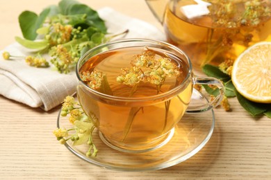 Photo of Cup of tea with linden blossom on wooden table