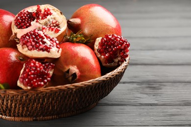 Delicious ripe pomegranates on grey wooden table, closeup. Space for text