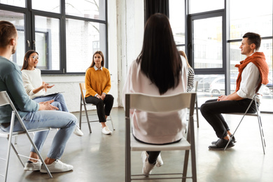 Photo of Psychotherapist working with patients in group therapy session indoors