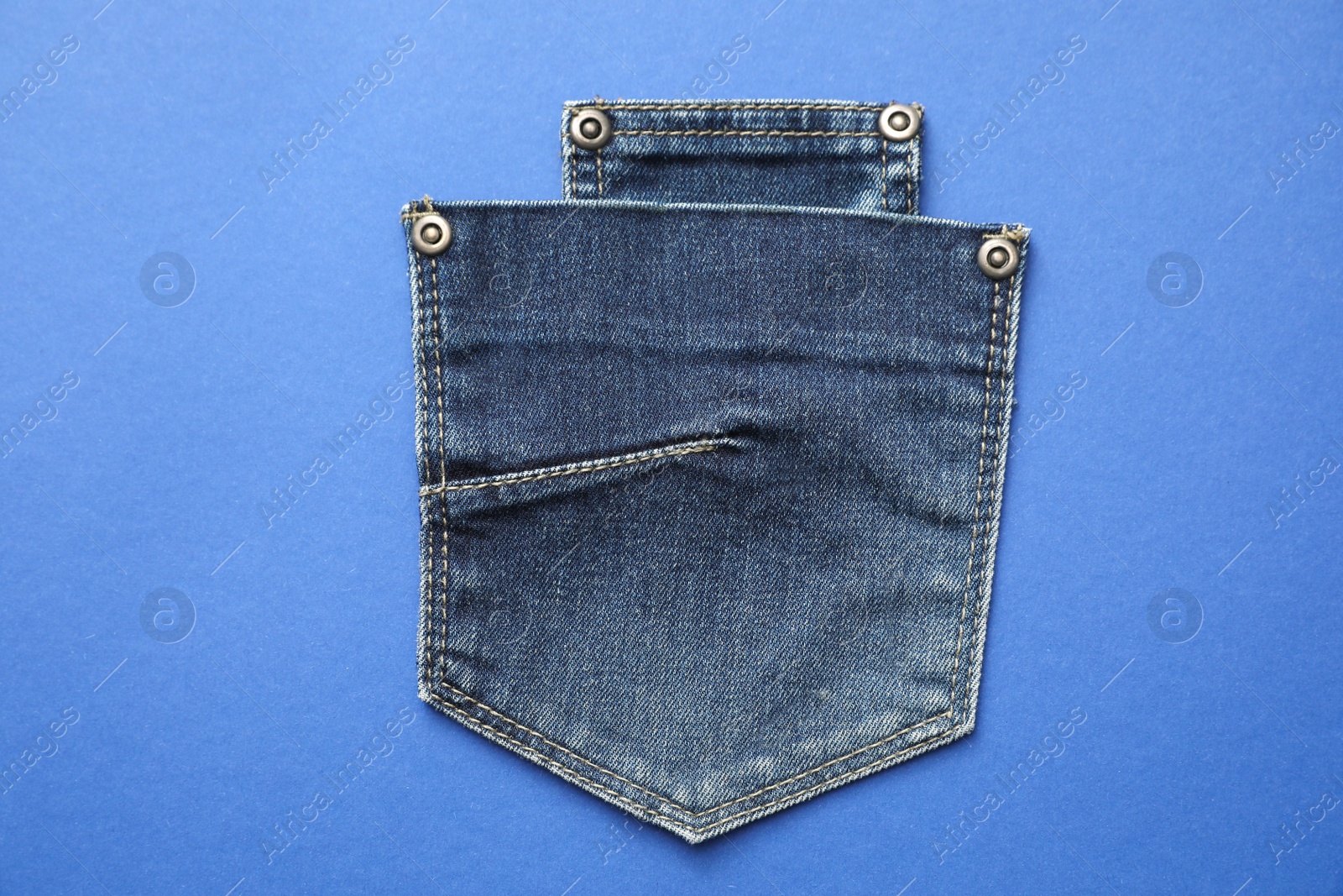 Photo of Stylish jeans pockets on blue background, top view