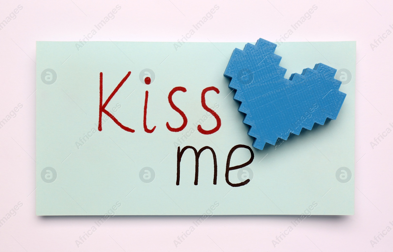 Photo of Card with phrase Kiss me and blue heart on white background, top view