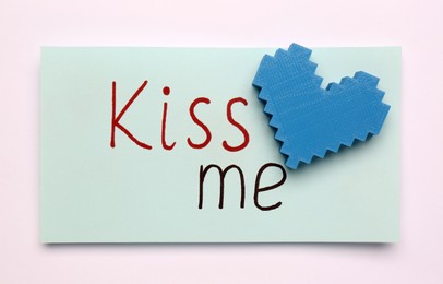 Photo of Card with phrase Kiss me and blue heart on white background, top view